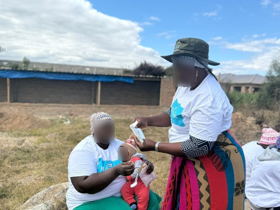 Outreach worker providing medication to a mother and child