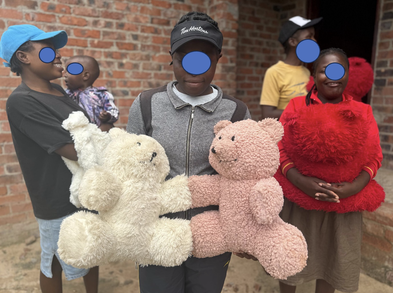 Young people and children receiving teddy bear gifts at a Mashambanzou Care Trust support activity